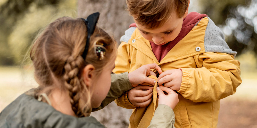 Menina ajudando o amigo a desatar o nó na blusa